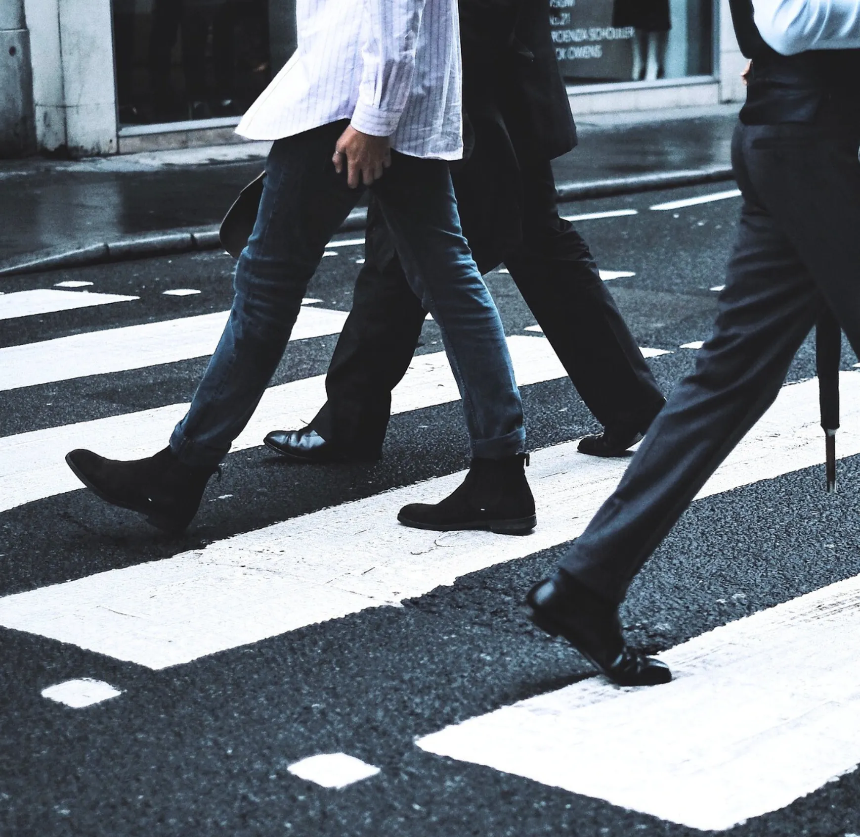 A group of people walking across a cross walk.